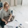 A woman carefully examines astrological charts while seated in a cozy indoor setting, showing focus and interest.